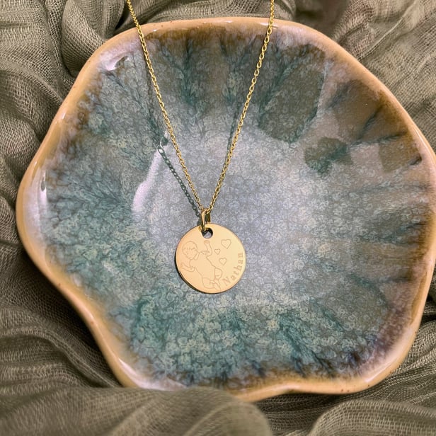 Collier médaille de naissance plaqué or avec illustration de bébé.